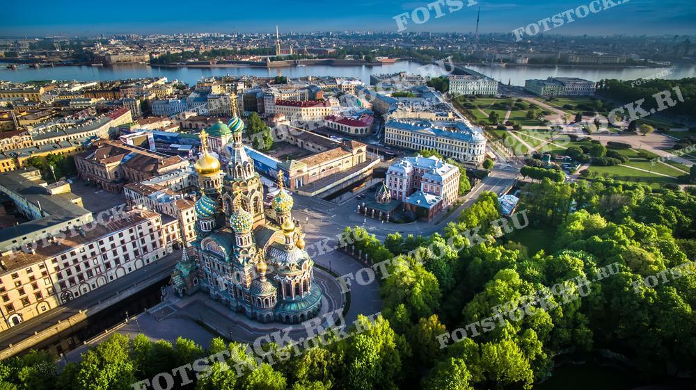 На фотографии представлен вид Санкт-Петербурга с высоты птичьего полёта. Центральное место занимает знаменитый Храм Спаса-на-Крови с его яркими цветными куполами, окружённый зеленью и городскими кварталами. Этот снимок может быть использован в туристических публикациях, исторических и культурных статьях, а также в образовательных материалах для демонстрации архитектуры и градостроительства Санкт-Петербурга. Также фотография подойдет для использования в рекламных материалах, поскольку она выгодно демонстрирует красоту и уникальность городской застройки.